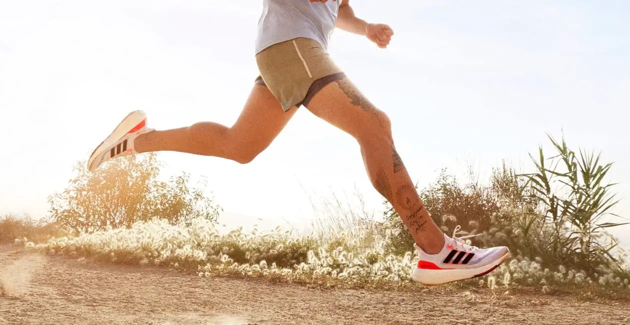Man running at the beach running on Adidas Ultraboost running shoes