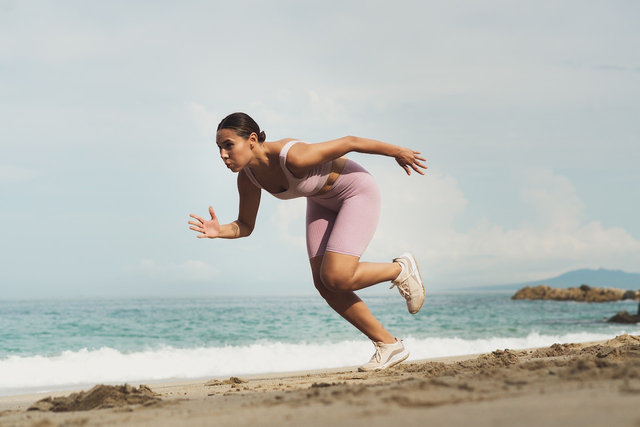Woman running at the sand in running shoes Nike 