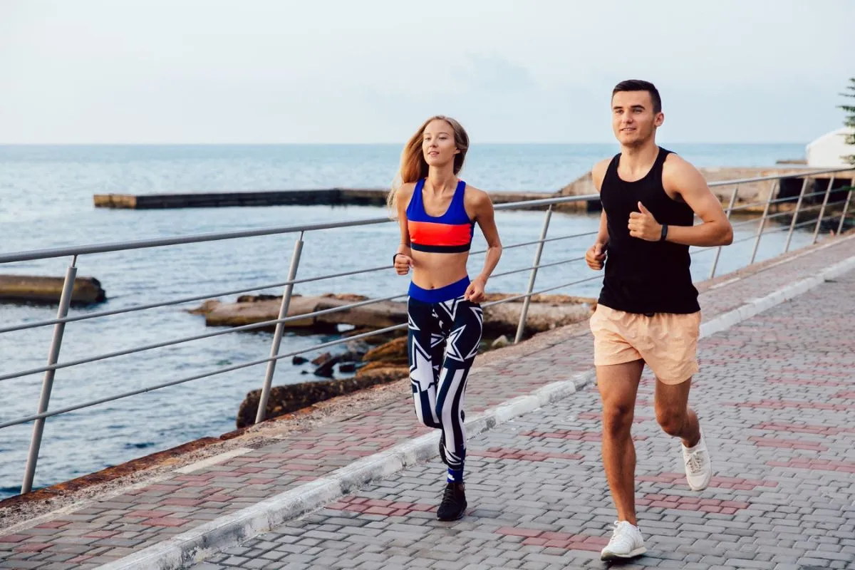 Two runners with a healthy and toned physique jogging by the seaside