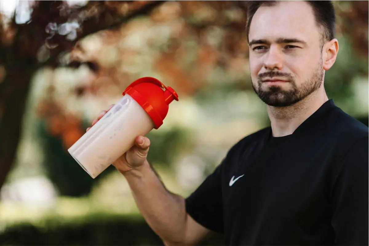 A man is making a shake with creatine or BCAA
